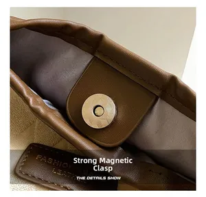 Détail de la boucle magnétique dorée sur un sac fourre-tout en cuir marron et tissu
