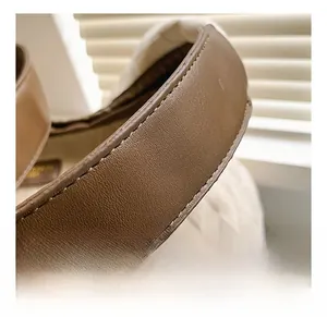 Détail de la bandoulière en cuir marron et du sac en toile matelassée beige avec couture