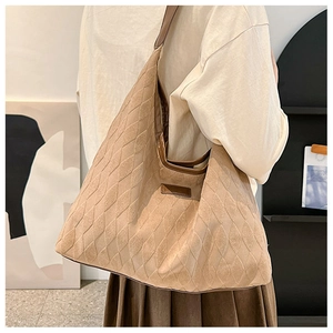 Détail de la texture matelassée et du patch logo sur le sac en daim porté