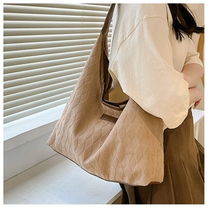 Détail du sac cabas matelassé kaki avec bandoulière en cuir brun et texture en suède