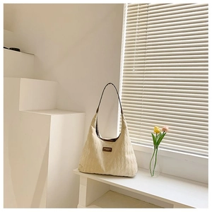 Gros plan du sac fourre-tout beige matelassé avec surpiqûres losanges et bordure brune