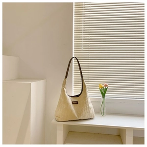 Gros plan du sac cabas matelassé beige avec logo en cuir marron et détails de bandoulière