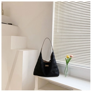 Détail d'un grand sac cabas matelassé noir en toile avec écusson marron et grand volume