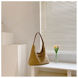 Détail d'un sac hobo matelassé kaki avec bandoulière en cuir marron dans un décor minimaliste