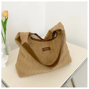 Détail du grand sac cabas en toile matelassée kaki avec finitions en cuir marron et logo