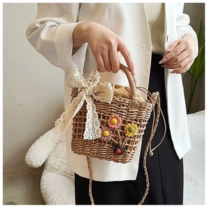 Macro detail of hand-woven straw bag with 3D floral accents and a beige lace bow