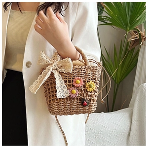 Close-up of handmade straw bucket bag with lace bow, floral patches and drawstring pouch
