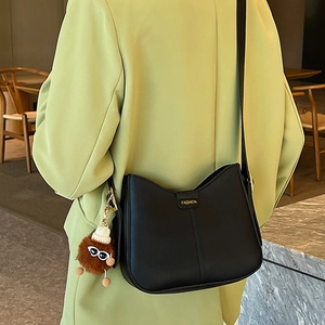 Black minimalist half-moon crossbody bag with wide strap and brown plush charm