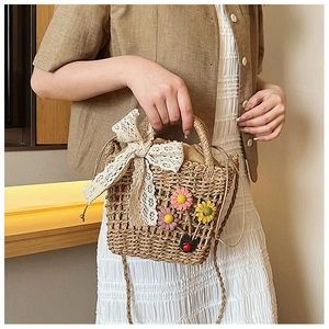 Close-up of woven straw bucket bag featuring white lace bow and floral appliques