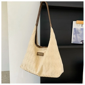 Détail du sac fourre-tout matelassé beige avec logo en cuir et bandoulière marron