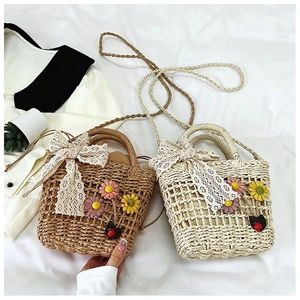 Detail of straw bucket bag with floral embroidery, lace bow, and ladybug accent