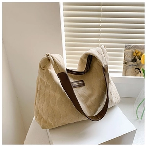 Détail de la texture matelassée et logo en cuir sur le grand sac cabas en toile