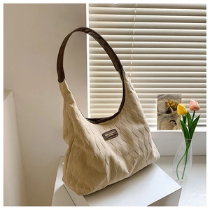 Détail du sac cabas beige surpiqué en toile avec poignée en cuir marron et patch logo