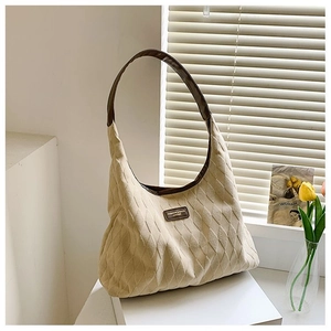 Détail du grand sac cabas matelassé beige avec poignées en cuir marron et plaque de mode