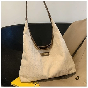 Détails de la toile matelassée blanc cassé et des finitions en cuir marron du sac cabas