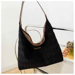 Détail d'un grand sac cabas matelassé avec bordure marron posé sur une chaise en métal stylée