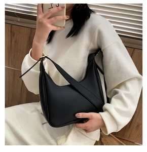 Detail of black matte crescent bag with cross-strap design and gold ring buckle detail