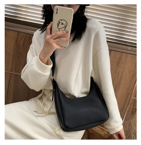 Minimalist black crescent hobo bag shown by model in soft home setting with natural light