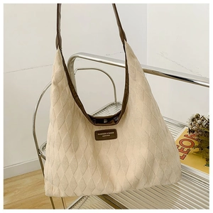 Détail du sac fourre-tout en toile matelassée avec garniture en cuir brun et logo en métal