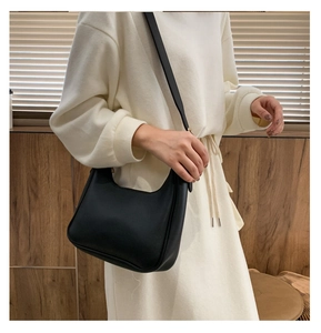 Detail of minimalist black leather hobo bag with litchi texture on a female model