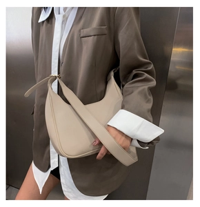 Close-up of beige moon bag with adjustable wide strap and gold hardware on model
