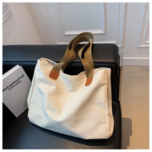 Dettaglio della borsa tote in tela con tracolla intrecciata marrone e rinforzi in ecopelle