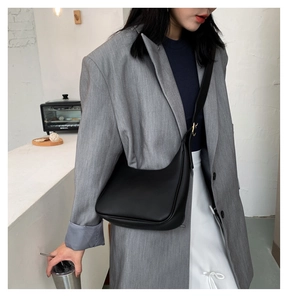 Detail of adjustable strap on a matte black crescent shoulder bag with gold hardware