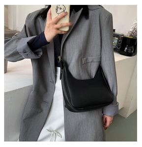 Minimalist black crescent crossbody bag styled with a professional grey blazer suit