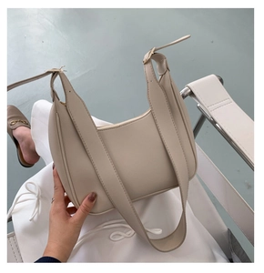 Macro detail of beige crescent hobo bag featuring wide strap and smooth faux leather texture