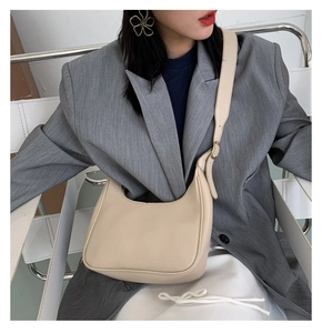 Model wearing a beige crescent moon crossbody bag with an adjustable leather strap