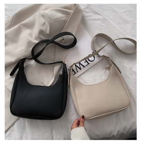 Detail of minimalist crescent moon bags in black and beige with gold hardware accents