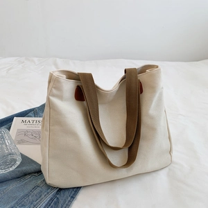 Borsa tote in tela minimalista con manici marroni su biancheria da letto bianca