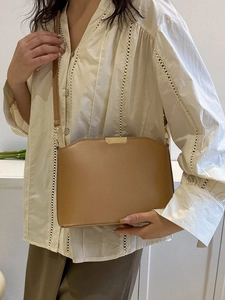 Braune Retro-Umhängetasche aus Leder im Beutelschick an Model bei natürlichem Licht