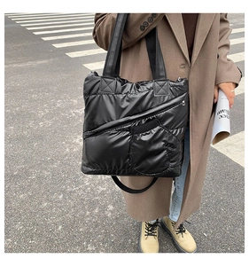Close-up of black quilted down tote bag featuring shiny nylon texture and side zipper