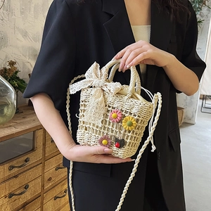 French straw bucket bag with floral decor, lace bow, and shoulder strap for beach vacation