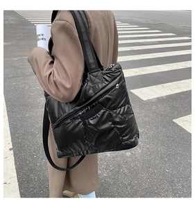 Detail of black quilted down tote bag with side zipper pocket and shoulder strap