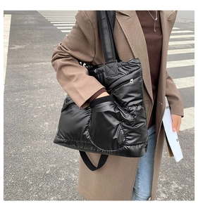 Close-up of black quilted puffer bag featuring creative glove-shaped front pocket detail