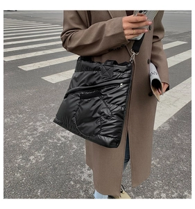 Detail of black quilted puffer tote bag featuring a unique glove-shaped pocket and strap
