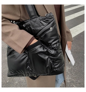 Detail of black puffer tote bag featuring a creative built-in mitten pocket for warming hands