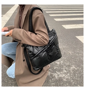 Detail of black quilted puffer tote bag featuring glossy nylon and a side zipper pocket