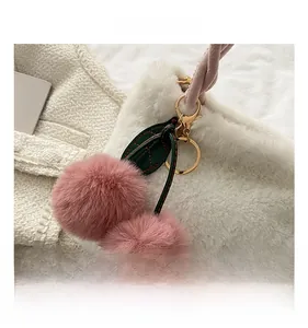 Detail of pink faux fur cherry charm with green leather leaf and golden metal clasp
