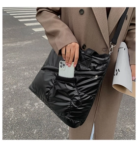 Close-up of black quilted down shoulder bag featuring a unique glove-shaped front pocket