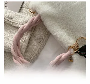 Detail showing plush white faux fur texture and woven pink velvet handle of the bucket bag