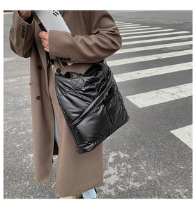 Outdoor shot of a black quilted down shoulder bag featuring lightweight nylon fabric