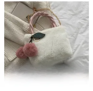 Mini plush bucket bag with pink handles and gold chain next to a phone for size comparison