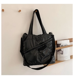 Close-up of black quilted down tote bag with wide nylon strap and zipper pocket