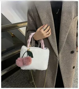 Detail of white plush bucket bag with pink woven handle and cute cherry charms
