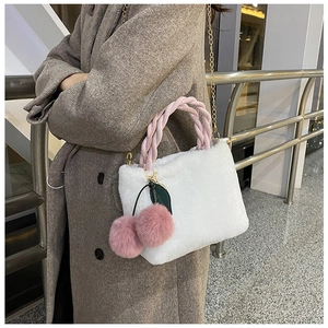 Detailed view of a white faux fur bucket bag featuring a pink cherry pom-pom charm and chain