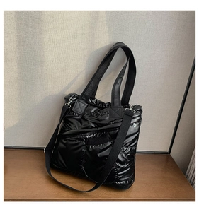 Detail of black quilted down tote bag featuring glossy fabric and wide shoulder straps
