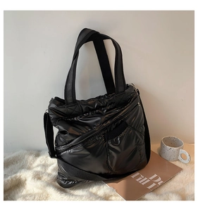 Detail of black quilted puffer tote bag with nylon texture and detachable strap